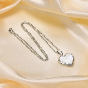 Detailed view of silver heart locket necklace with mother of pearl inlay on silk