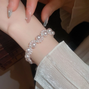 Close-up of pearl beaded bracelet with diamond-encrusted metal spacers on a wrist