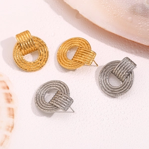 Detail of vintage spiral textured stud earrings in gold and silver finish on seashell