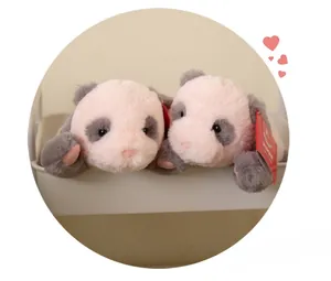Macro shot of two soft pink and grey panda plush dolls sitting in a white tray