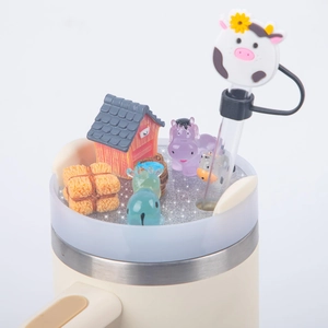 Detail of 40oz tumbler lid with farm animal miniatures, glitter liquid, and cow straw cover