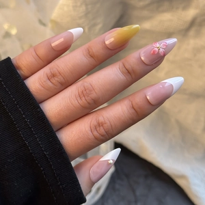 Macro detail of almond press-on nails featuring 3D pink flowers and yellow gradients