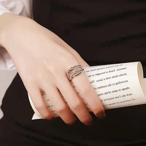 Detail eines silbernen Angst-Rings mit Perlen auf Hand mit Vintage-Papierhintergrund