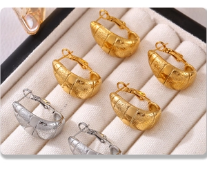 Détail macro de boucles d'oreilles croissant en or et argent sur velours blanc