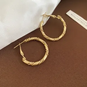 Minimalist twisted geometric gold hoop earrings with matte finish and elegant silk accent