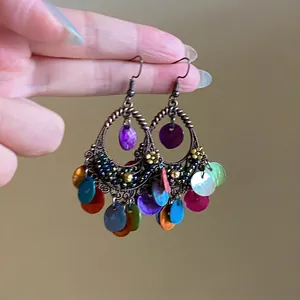 Close-up of bohemian drop earrings with colorful sequins and vintage bronze metal frames
