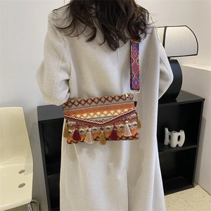 Close-up of bohemian woven crossbody bag with colorful tassels and wide patterned strap
