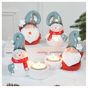 Close-up of ceramic Santa and snowman candle holders on a snowy decorative surface