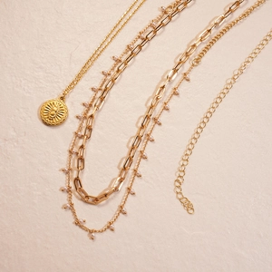Detail of 18K gold plated multi-layer necklace with sun coin and paperclip chain