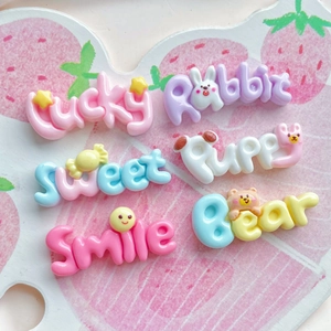 Close-up of colorful resin alphabet charms including Lucky and Smile designs for DIY crafts