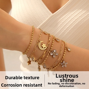 Detail of layered gold bracelets with moon, star, and butterfly charms on wrist
