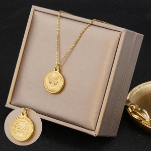 Detail shot of golden double-sided coin pendant necklace featuring Elizabeth II engraving