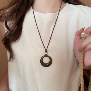 Gros plan d'un collier pendentif rond en acrylique vintage sur un haut en lin
