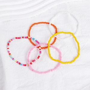 Detailed flat lay of 5-piece colorful bohemian bead bracelet set on white linen texture