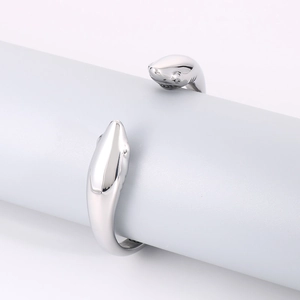 Polished stainless steel open cuff bracelet with double dolphin design on blue stand
