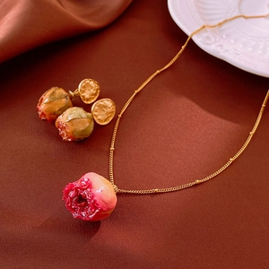 Detailed close-up of golden rose pendant necklace and earrings on red silk background