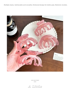 Macro detail of high-quality thick pink acetate hair claw clip with golden accent logo