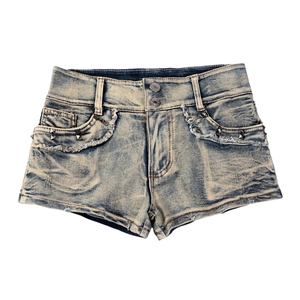 Detail der Denim-Shorts mit Metallnieten, Fransenrand und Vintage-Waschung