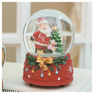 Macro detail of Christmas snow globe with Santa Claus and a red knitted base