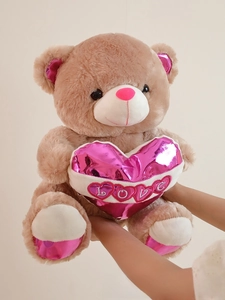 Close-up of light brown teddy bear featuring pink metallic leather LOVE heart and soft fur