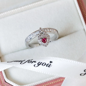 Detailed close-up of heart-shaped ruby ring with square-cut zircon pavé in a gift box