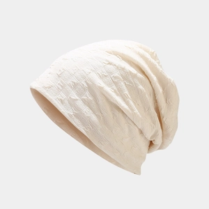 Close-up of cream knit beanie featuring a textured square grid pattern and soft fabric