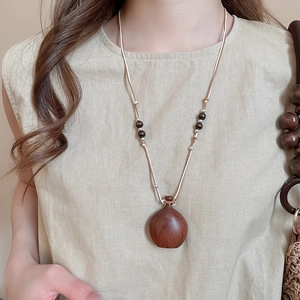 Close-up of vintage wood kettle pendant necklace with wax rope and natural beads