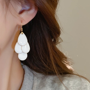 Close-up of elegant white layered teardrop fringe earrings worn on model's ear