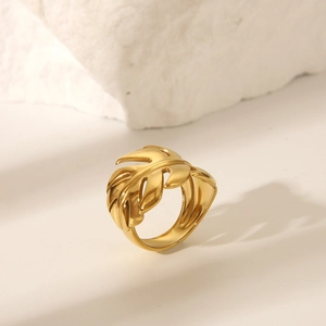 Macro detail of gold-plated hollow leaf ring against a minimalist stone background