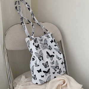 Detail of canvas tote bag featuring black butterfly prints and branded woven label