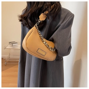 Detail of light brown crescent underarm bag with gold chain and fashion logo label