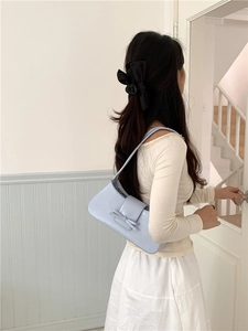 Close-up of a light blue underarm baguette bag with a decorative bow on the shoulder strap