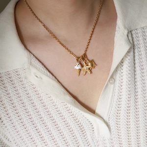 Detailed close-up of gold chain necklace with ice cream, seahorse and turtle charms