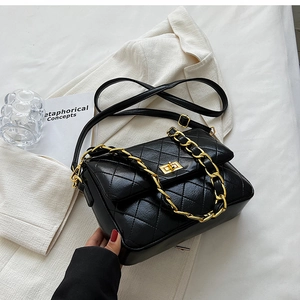 Detail of black quilted crossbody bag with gold chain strap and metal swivel lock
