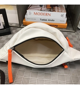 Top view of white waterproof chest bag showing beige lining and orange zipper puller detail