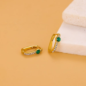 Detailed macro view of gold-plated hoop earrings with green zircon and side diamonds