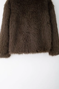 Close-up detail of dark brown faux fur jacket showing fluffy texture and premium stitching