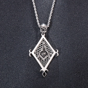 Macro shot of silver skull pendant with masonic eye symbol on twisted chain