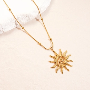 Macro detail of gold sun pendant necklace with spiral center on a textured surface