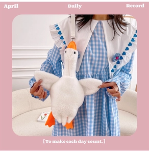 Model wearing a white plush goose crossbody bag with orange beak and adjustable strap