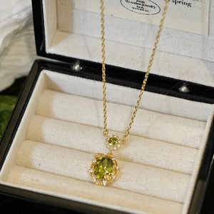 Detailed macro shot of 18K gold plated necklace with oval emerald green zircon and diamonds