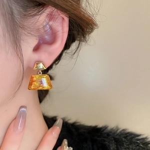 Detail of amber trapezoid resin earrings with gold plating on model for elegant style