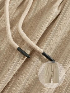 Detail of apricot knit drawstring shorts featuring premium textured terry jacquard fabric