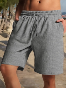 Close-up of men's heavy grey shorts featuring herringbone texture and drawstring waist