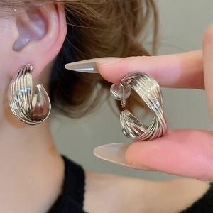 Detailed macro view of silver twisted C-shaped earrings with multi-layered metallic texture