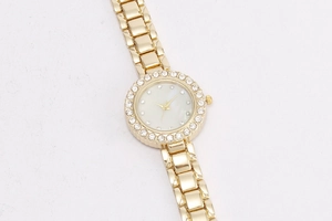 Detailansicht der goldenen Strass-Uhr mit weißem Perlmutt-Zifferblatt in Nahaufnahme