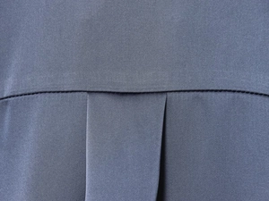 Detailed close-up of dark grey satin fabric featuring a professional back box pleat design
