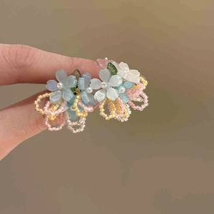 Close-up of handmade beaded flower tassel earrings with blue and white resin petals