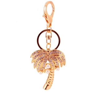 Golden coconut tree keychain with purple rhinestones and white pearls on white background