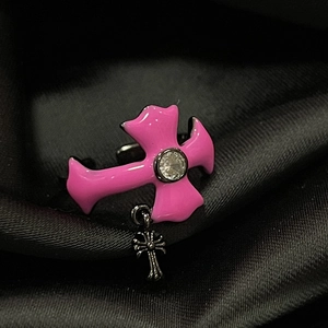 Detail of pink cross ring with clear crystal and metal charm on black silk
